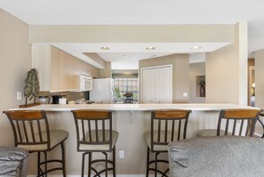 A kitchen with a central island, bar stools, and a view to the dining area.