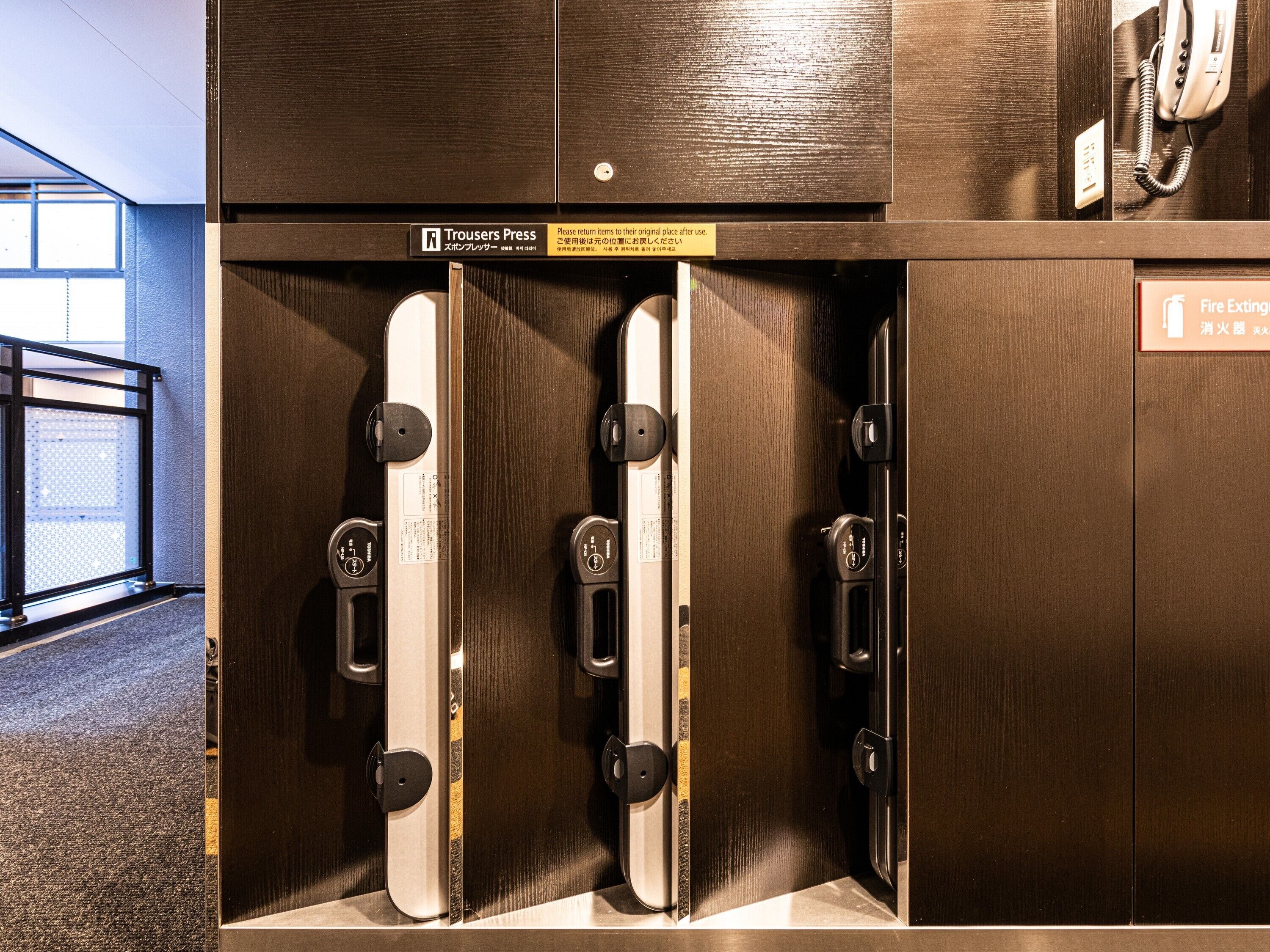 Une chambre d’hôtel équipée d’une armoire en bois, d’un extincteur et d’un panneau indiquant le numéro de la chambre.