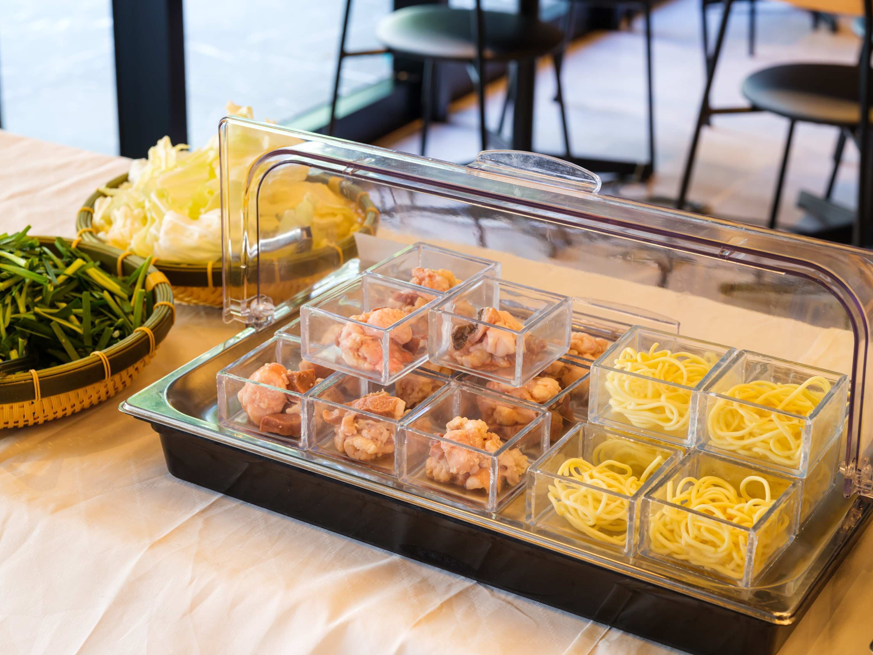 Een buffet met diverse soorten eten, waaronder garnalen, spaghetti en groenten.