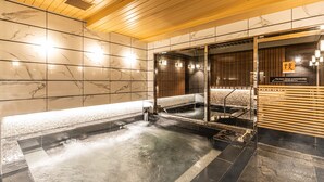 Un moderno espacio de spa con suelo climatizado, techo de madera y mampara de vidrio.