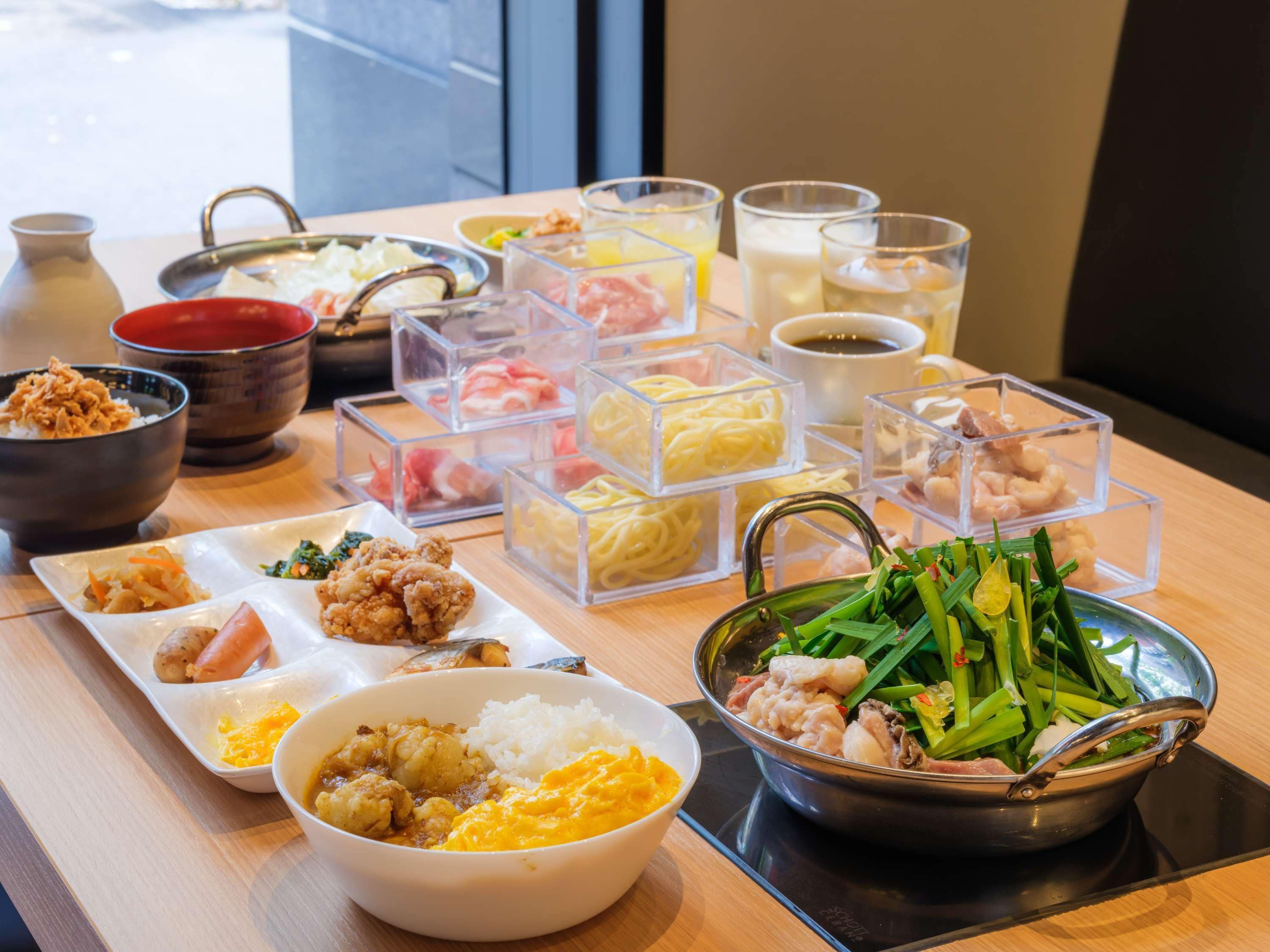 A variety of dishes including rice, vegetables, and meat, served on a wooden table with clear containers and bowls.