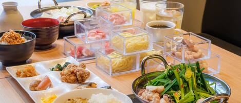 A variety of dishes including rice, vegetables, and meat, served on a wooden table with clear containers and bowls.