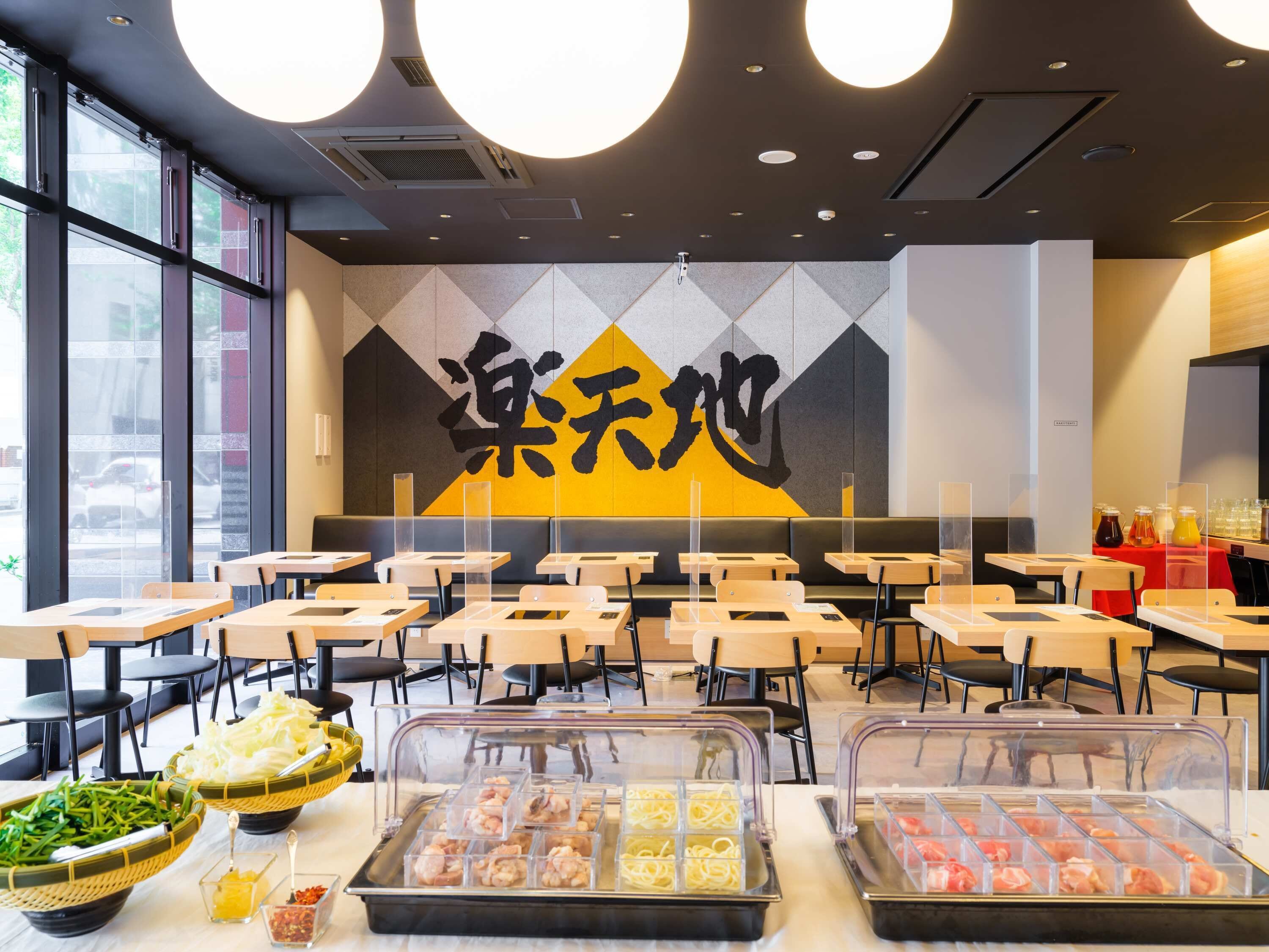 A restaurant with a modern interior, featuring a large wall mural, multiple seating areas, and a variety of food options displayed in clear containers.