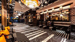 Un vestíbulo lujoso con piso de mármol, zonas de estar y un bar con pared decorativa.