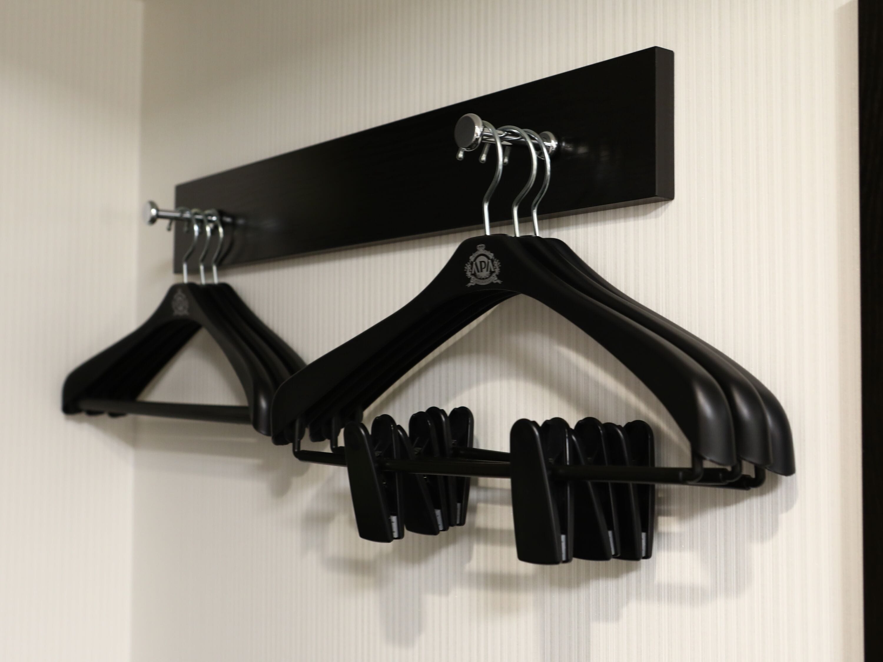 A wall-mounted coat rack with two black hangers.