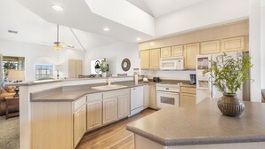 Una cucina moderna con un'isola grande, elettrodomestici integrati e mobili da cucina in legno chiaro.