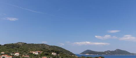 A coastal town with buildings on a hillside, boats in the water, and a clear sky.
