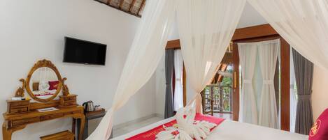 A bedroom with a canopy bed, a wooden dresser, a television, and a view of the outdoors.