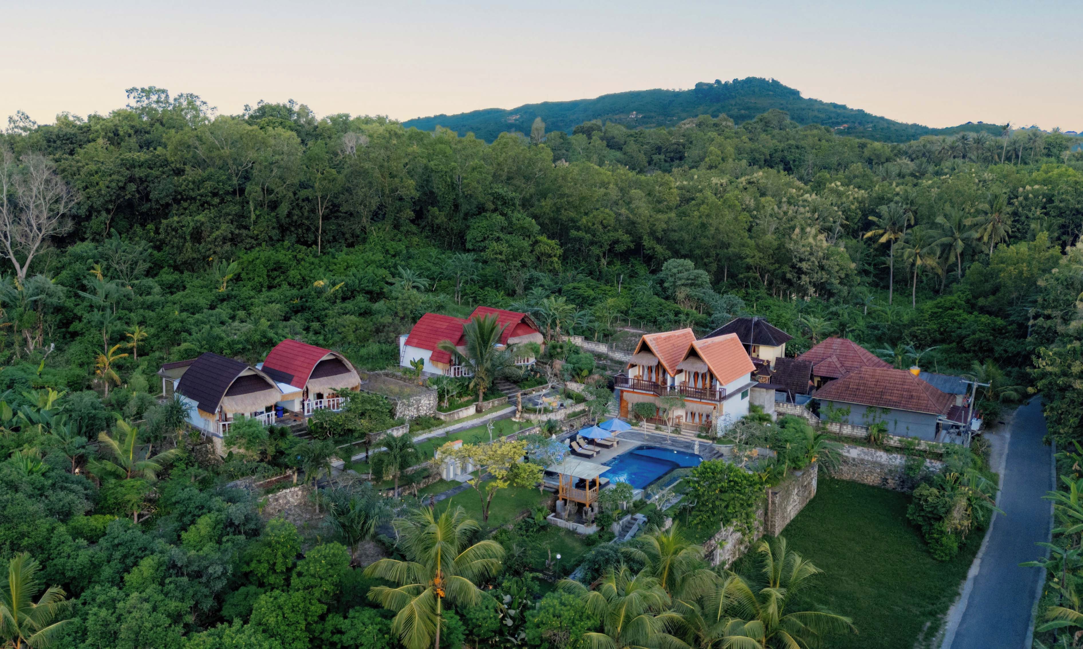 A resort with multiple buildings, a swimming pool, and lush greenery.