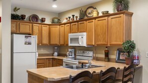 A kitchen with wooden cabinets, a refrigerator, a microwave, a stove, and a sink. - Walk-In 2BR Branson Condo Near Strip | Sleeps 7 | Golf + Ticket Deals (Branson)