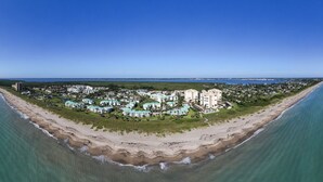 Eine Luftaufnahme eines Küstenresorts mit Strandhäusern, einer Marina und einem strahlend blauen Himmel.