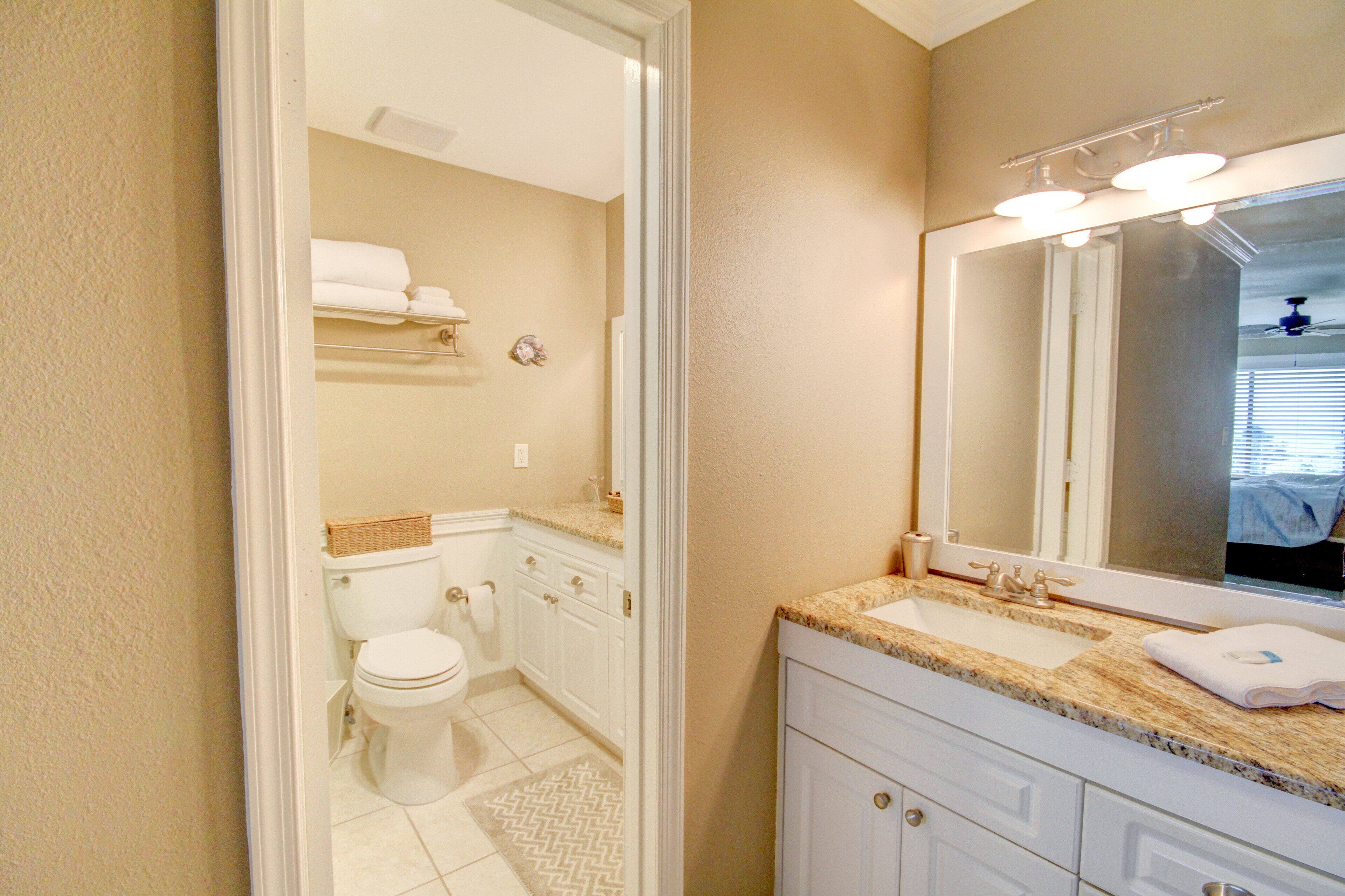 A bathroom with a toilet, sink, and mirror.