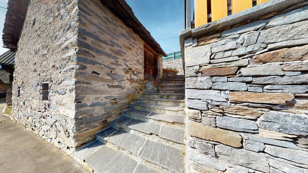 A stone staircase leading to a wooden door, part of a traditional stone building with a sloped roof. - Baita Dal Gat (Faido)