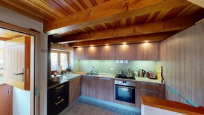 A modern kitchen with wooden cabinets, a stainless steel sink, and a built-in oven. - Baita Dal Gat (Faido)