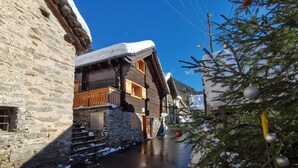 A narrow street with stone buildings, wooden balconies, and a snow-covered tree. - Baita Dal Gat (Faido)