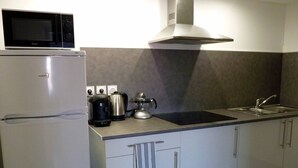Una cocina equipada con microondas, cafetera, hervidor y pileta.