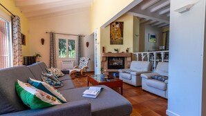 Una sala de estar con sofá, sillones, chimenea y comedor.