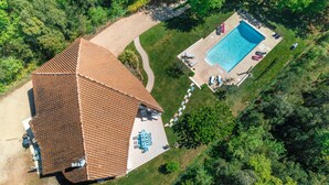 Vista aérea de una casa con piscina, rodeada de vegetación.