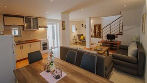 Un apartamento moderno con comedor, cocina, sala de estar y escalera.