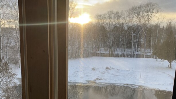 Una ventana con vista a un paisaje nevado y un atardecer.