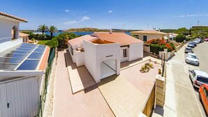 Un barrio residencial con una casa blanca, un panel solar y vistas al mar.