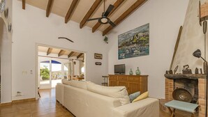 Una sala de estar con sofá, televisión, chimenea y un cuadro en la pared.