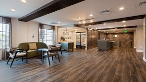 A spacious lobby with a modern bar area, seating arrangements, and a herringbone-patterned wall. - Homewood Suites by Hilton St. Augustine San Sebastian (St. Augustine)