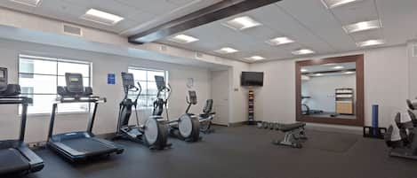 Een sportschool met loopbanden, elliptische trainers en losse gewichten.