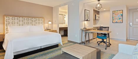 Una habitación de hotel con una cama grande, un escritorio, una silla, un sofá y una mesita.