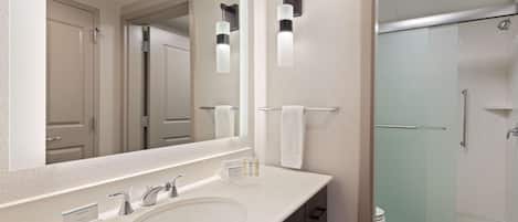 Un baño moderno con un espejo grande, dos lavamanos, ducha e inodoro.