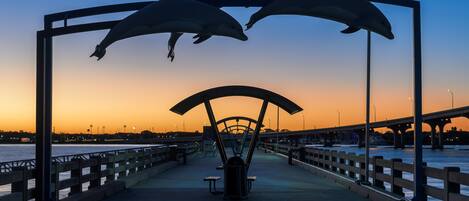 A bridge with a sculpture of dolphins and a bench in the center.