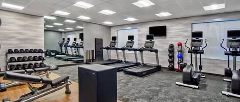 A gym with treadmills, weight machines, and dumbbells.