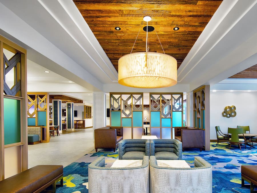 A spacious lobby with a high ceiling, a large hanging light fixture, and a colorful carpet.
