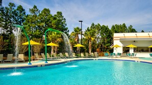 A swimming pool with clear blue water, surrounded by lounge chairs and yellow umbrellas.