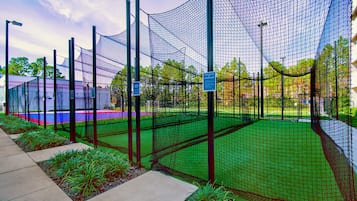 Ein Baseballfeld, umgeben von einem Netz, mit blauem Himmel.