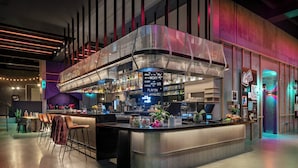 A modern bar area with a curved counter, bar stools, and a neon sign.