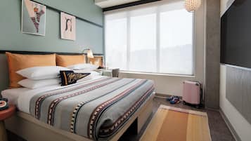 Quarto de hotel moderno com uma cama grande, vista para a cidade e uma janela panorâmica.
