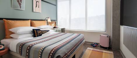 A modern hotel room with a large bed, a view of the city, and a window with a view.