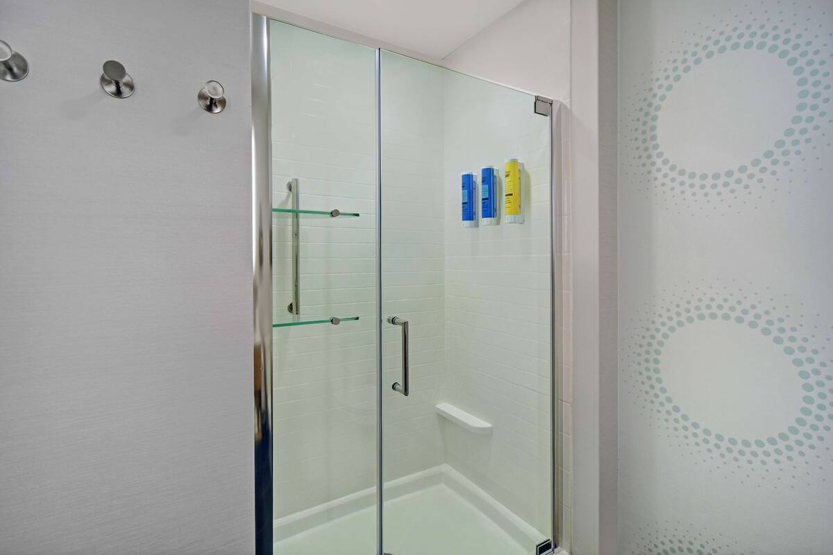 A glass-enclosed shower with a glass door, a glass shower door, and a glass shower curtain.
