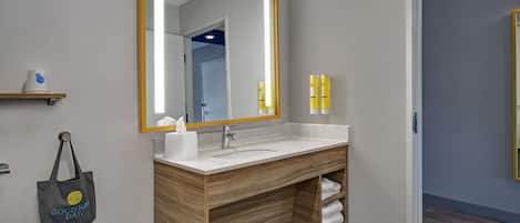 Un baño moderno con un mueble de tocador de madera, un espejo grande y un estante para toallas.