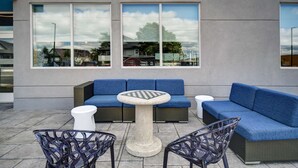 Un área de estar al aire libre con un sofá azul, una mesa redonda y sillas de mimbre.
