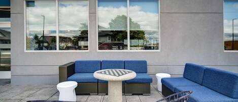 An outdoor seating area with a blue sofa, a round table, and wicker chairs.