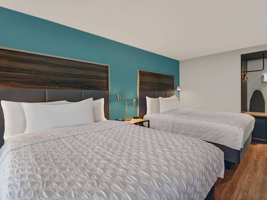 A hotel room with two beds, teal walls, and wooden headboards.