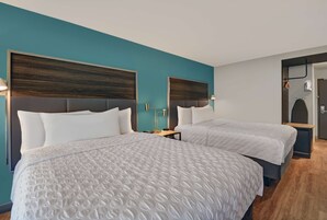 Una habitación de hotel con dos camas, paredes color turquesa y cabeceros de madera.