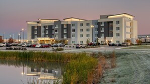 Ein mehrstöckiges Hotel mit modernem Design, mit Parkplatz und einem Wasserlauf davor.