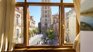 Une vue depuis une fenêtre donnant sur une rue bordée de bâtiments historiques, dont une tour imposante.