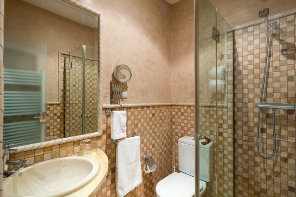 Un baño con lavamanos, inodoro y ducha con mampara de vidrio.