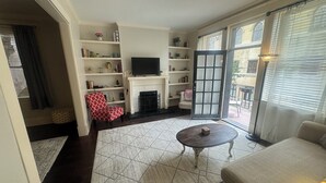 Un salon avec une cheminée, un téléviseur, un fauteuil à motifs rouges et un canapé.