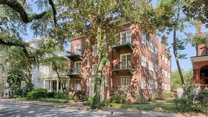A multi-story brick building with balconies, surrounded by trees and greenery. - Forsyth Executive Rental (Savannah)