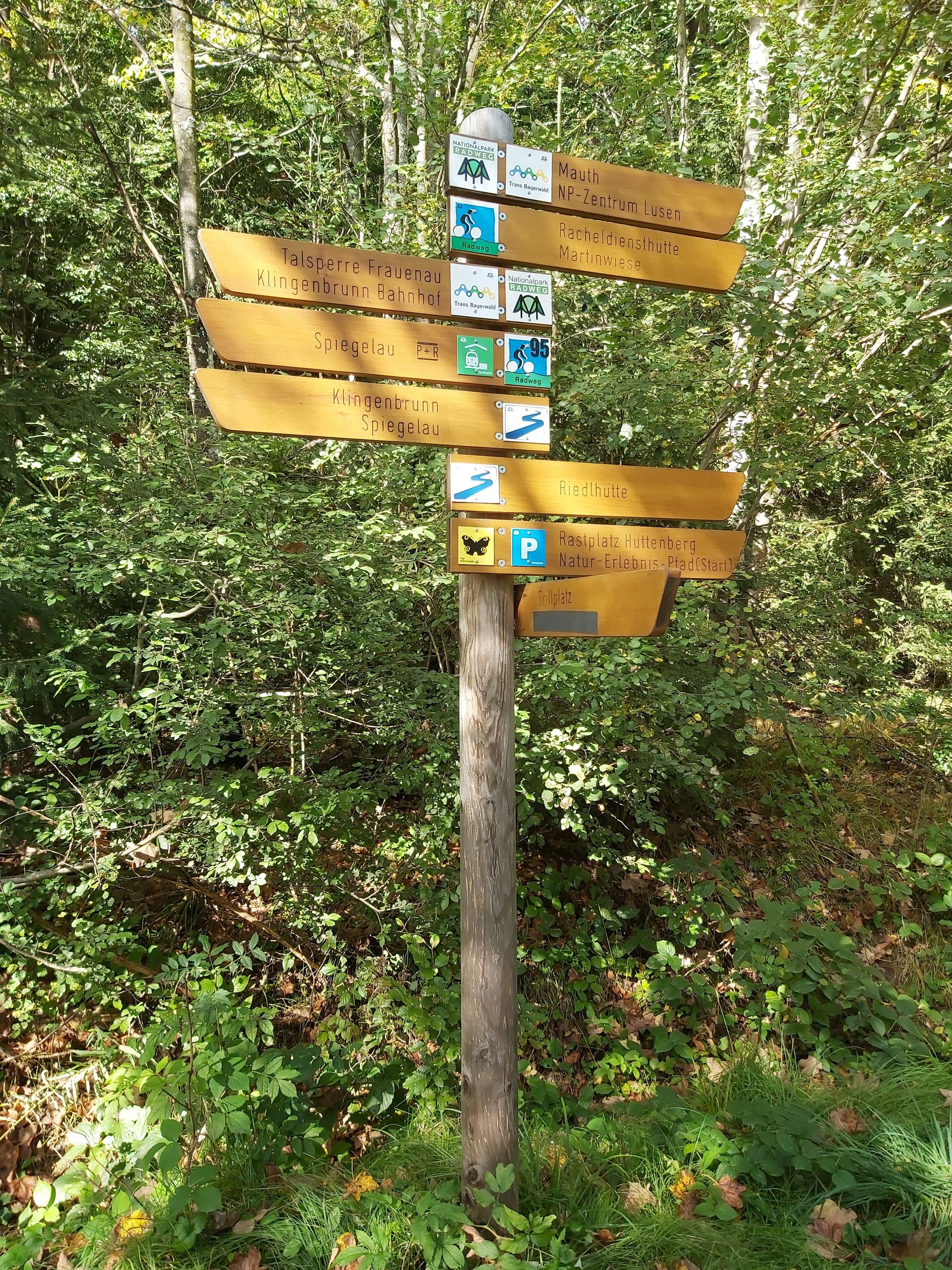 A wooden directional signpost with multiple arrows pointing to various destinations.